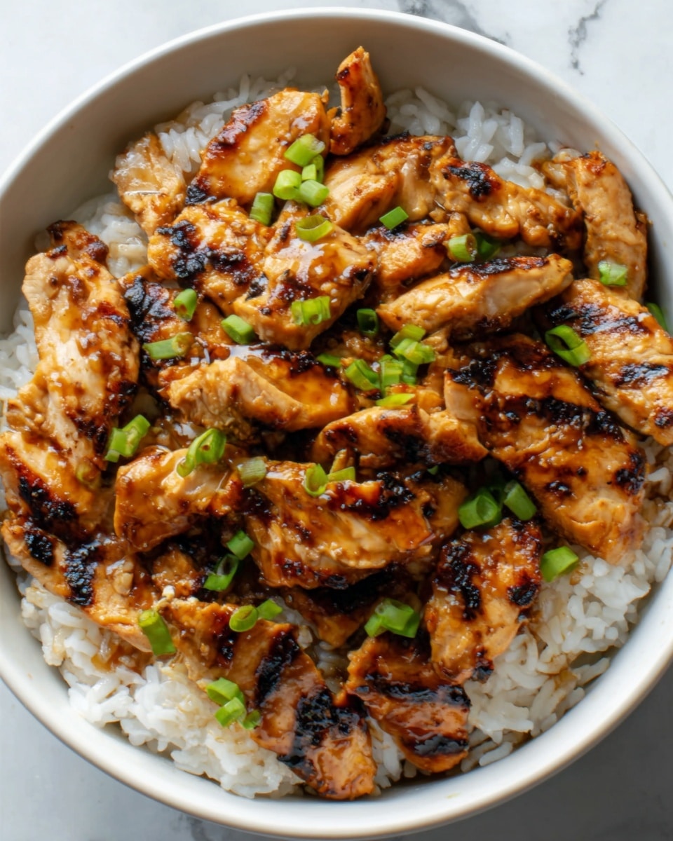 A white bowl filled with white rice at the bottom layer, topped with many pieces of grilled chicken that have a shiny, dark brown glaze and slightly charred edges. Small green onion pieces are scattered on top, adding a fresh green color contrast. The chicken pieces are piled high, covering most of the rice. The photo is taken with a white marbled surface in the background. photo taken with an iphone --ar 4:5 --v 7