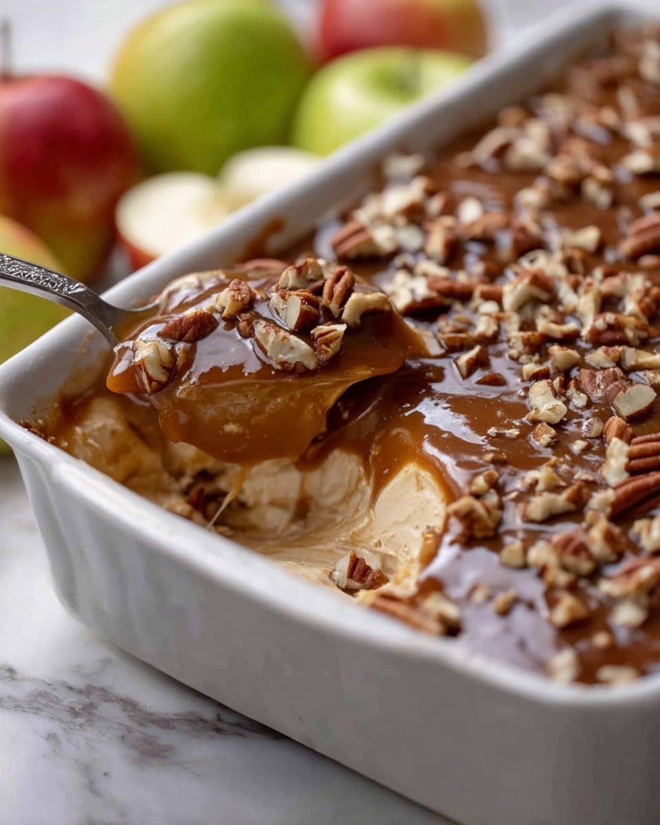 A close-up view of a white rectangular baking dish filled with a layered dessert. The bottom layer is creamy and smooth, light beige in color, topped with a thick, glossy caramel layer that is dark brown with a shiny texture. Chopped pecans are scattered over the caramel layer, adding a rough texture with their warm brown color. A spoon is scooping out a mix of the creamy base and caramel with pecans. In the background, there are sliced green and red apples placed on a white marbled surface. photo taken with an iphone --ar 4:5 --v 7