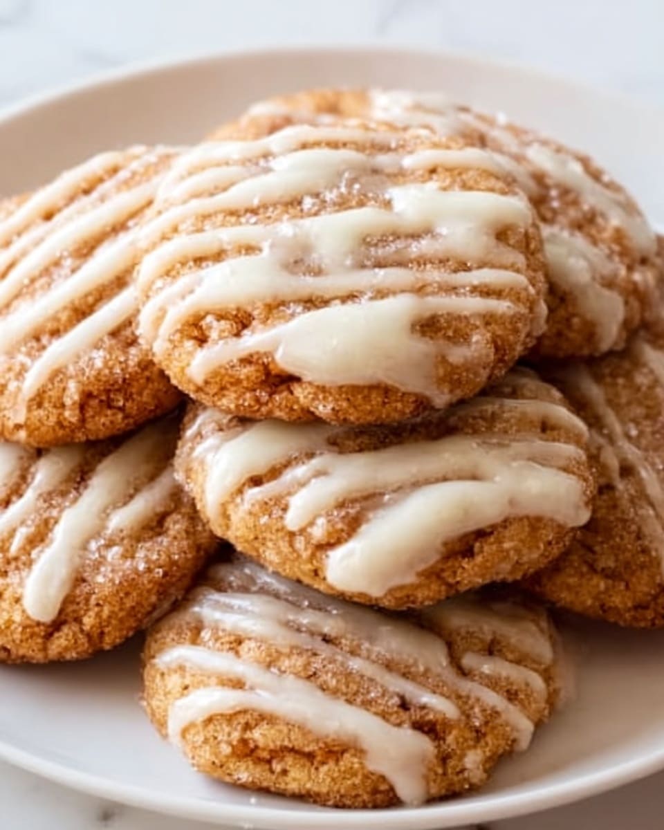 The image shows a close-up of a stack of round cookies on a white plate. There are two to three layers of cookies, each cookie having a golden-brown color with a slightly crispy texture. The cookies are drizzled unevenly with creamy white icing, which adds a smooth and glossy contrast on top of the rough surface of the cookies. The plate is set on a white marbled surface, giving a clean and bright look to the scene. Photo taken with an iphone --ar 4:5 --v 7