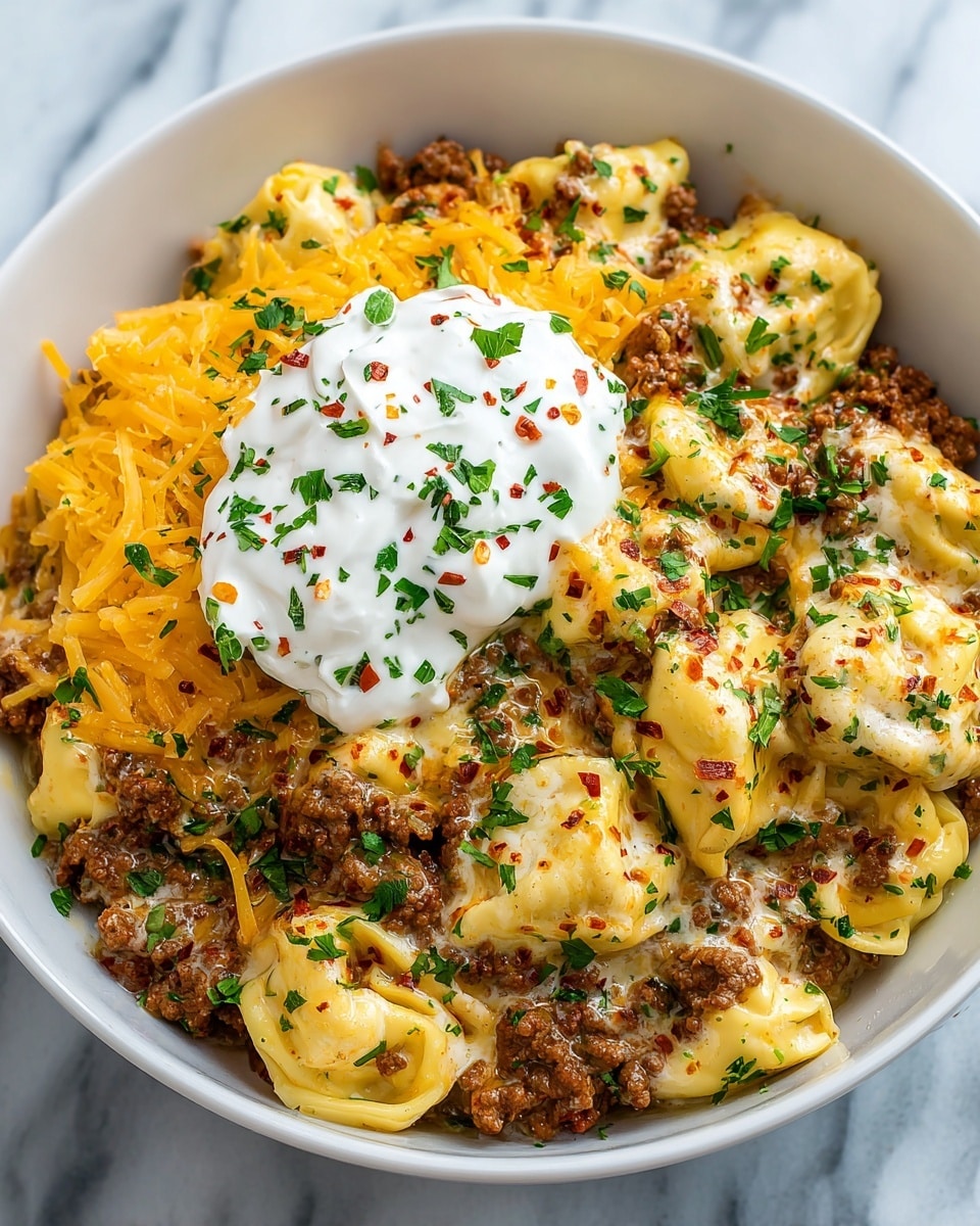 A white bowl filled with three layers of food: the bottom layer is creamy ground beef seasoned with small red and black spices, the middle layer is yellow cheese melted over lots of stuffed tortellini pasta, and the top layer is a dollop of white sour cream sprinkled with green chopped herbs and more melted yellow cheese strands scattered around. The food looks smooth, creamy, and cheesy with a mix of soft pasta shapes and textured meat pieces, all set against a white marbled surface. photo taken with an iphone --ar 4:5 --v 7